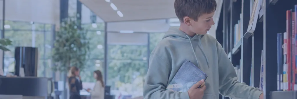 Jongen bekijkt boek in boekenkast