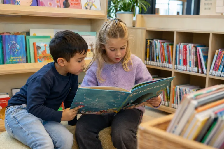 twee kinderen zitten en lezen uit een boek